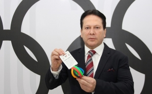 Daniel Aceves, presidente de Medallistas Olímpicos de México, sostiene las pulseras que promueven los cinco valores del deporte.